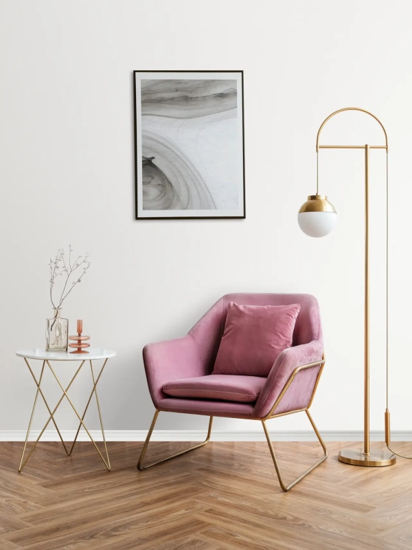 Picture frame with abstract art by a pink velvet armchair